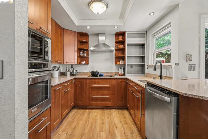U-shaped kitchen featuring wood-finish flooring, light-toned countertops, and warm-toned cabinetry