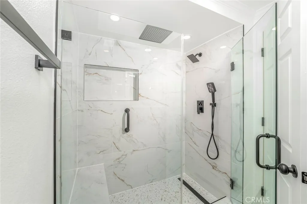 Beautiful step in shower with three shower heads and a seat!