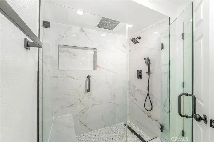 Beautiful step in shower with three shower heads and a seat!