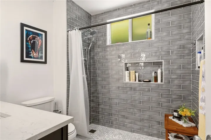 Beautifully remodeled bathroom showcasing a modern walk-in shower with stylish tile and dual built-in shower niches.