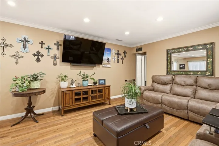 Bright and inviting living room featuring beautiful hardwood floors, recessed lighting, and crown molding.