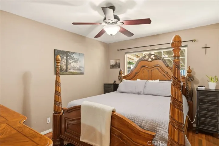 Comfortable primary bedroom featuring hardwood flooring, a ceiling fan, and abundant natural light.