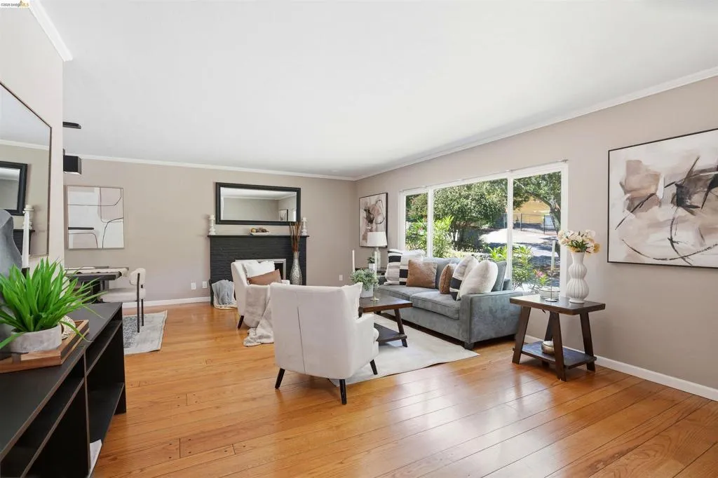 Spacious living area featuring wood-finish flooring, a fireplace with a dark-tiled surround, and large windows