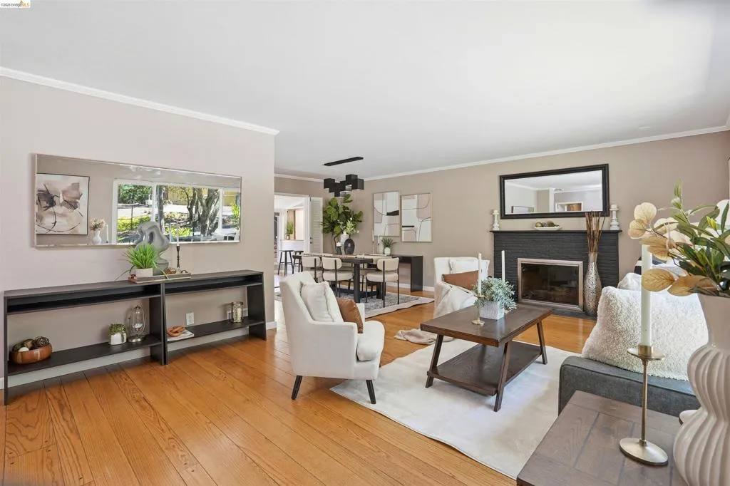 Hardwood flooring throughout a spacious living area featuring a fireplace with a dark brick surround and a contrasting light mantel