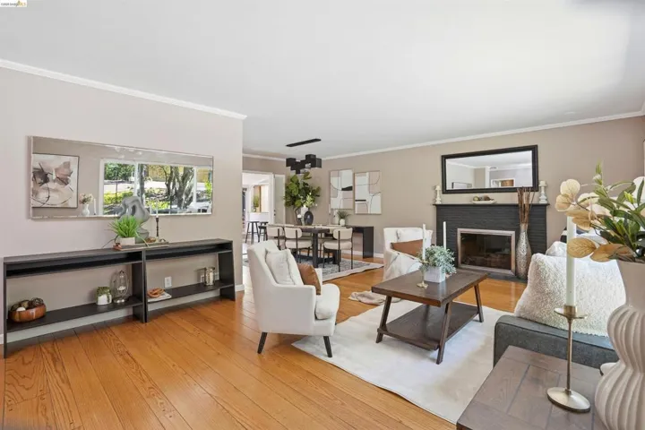 Hardwood flooring throughout a spacious living area featuring a fireplace with a dark brick surround and a contrasting light mantel