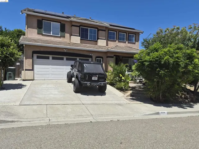Two-story stucco residence featuring a two-car garage, concrete driveway, and solar panels