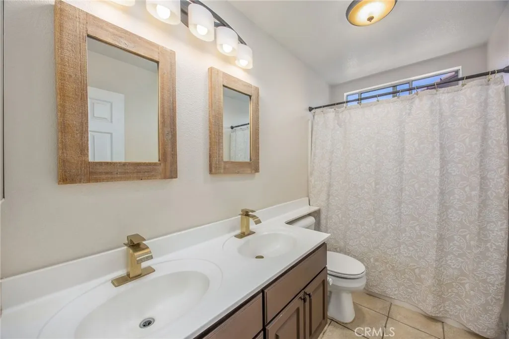 Upstairs hall bathroom featuring a dual-sink vanity and shower/tub combination