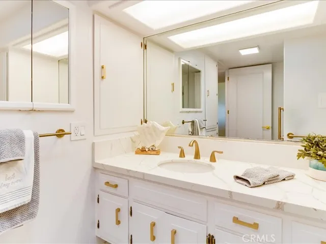 Main bathroom vanity with stone counter and brass hardware and fixtures