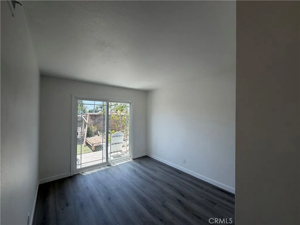 South-side bedroom with new flooring, natural light, and sliding door access to the backyard.