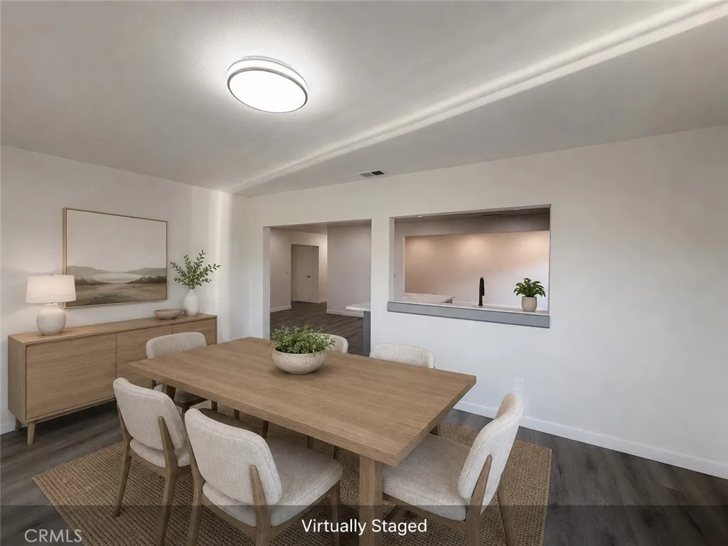 Virtually staged dining room featuring upgraded flooring, modern lighting, and an open pass through to the kitchen with direct backyard access.