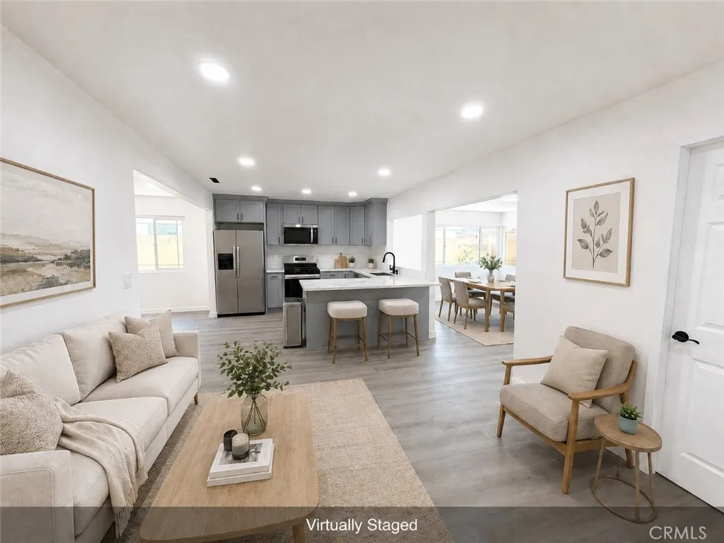 Virtually staged living area with new flooring, recessed lighting, open kitchen with island, and adjoining dining area.