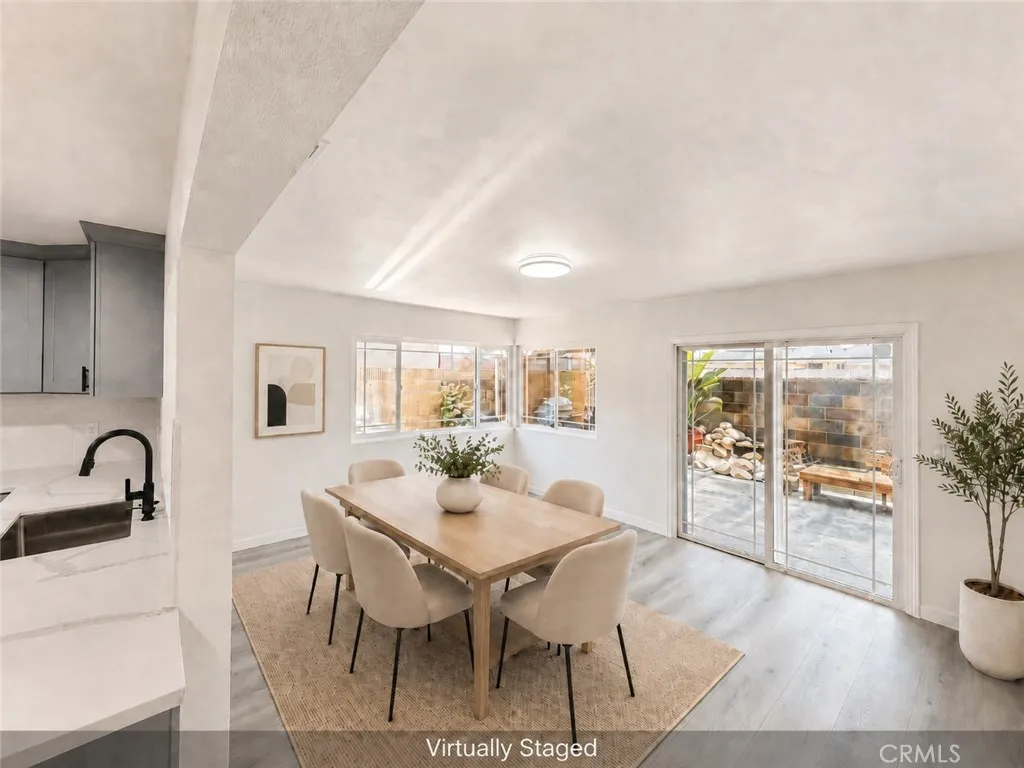 Virtually staged dining area with new flooring, fresh paint, natural light, and sliding door access to the backyard.