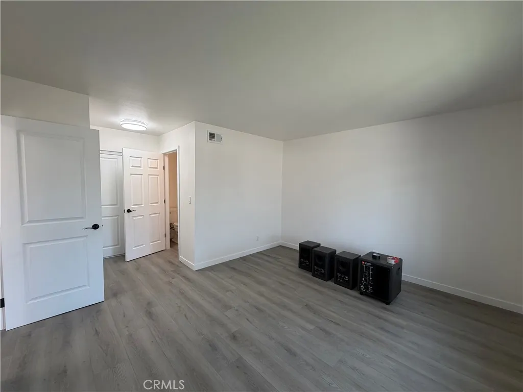Primary bedroom with wide-plank flooring, updated doors, neutral paint, and access to the primary bathroom.