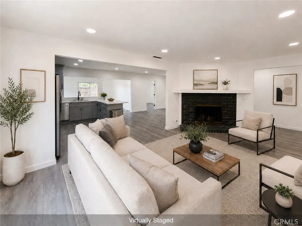 Virtually staged living room with new recessed lighting, fireplace, new flooring and open flow to the kitchen.