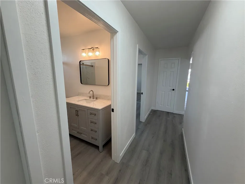 Secondary bathroom with new Quartz vanity, modern lighting, and hallway access to bedrooms and coat closet.