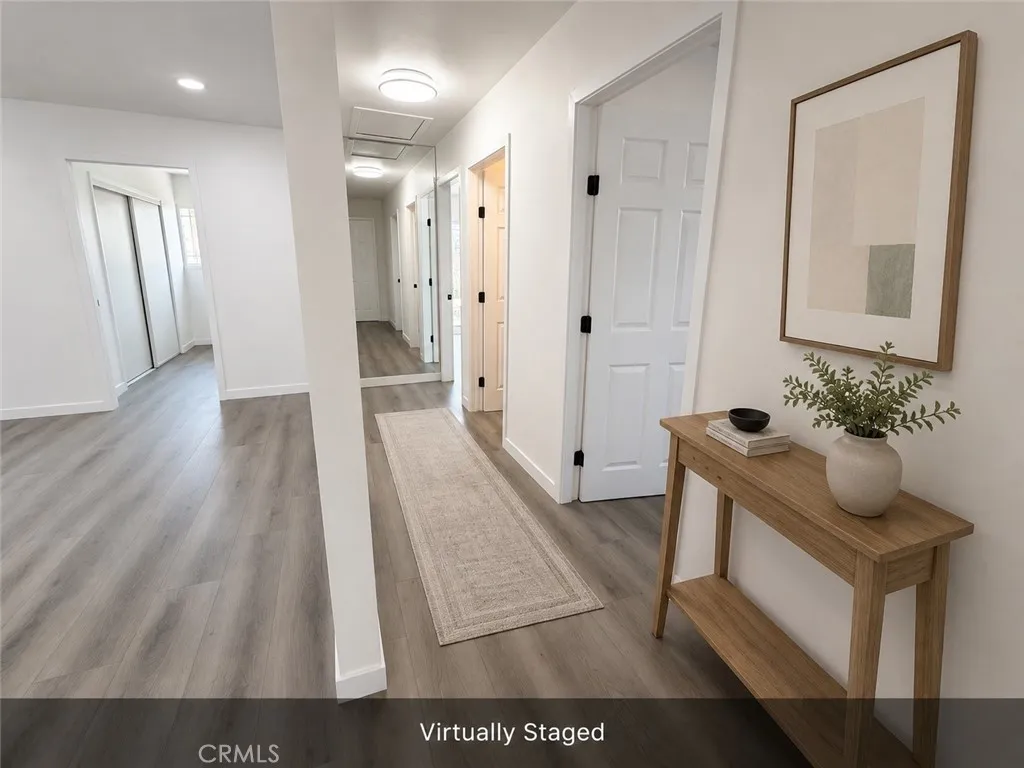 Virtually staged hallway with new flooring, fresh paint, updated lighting, new doors, and access to bedrooms and bathroom.
