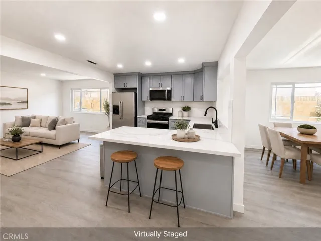 Open concept kitchen with new quartz island, new cabinetry, new recessed lighting, new flooring, and adjoining living and dining areas.
Virtually staged.