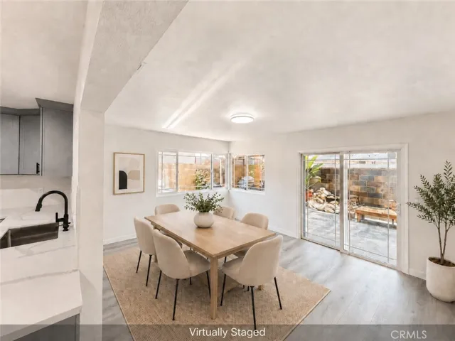 Virtually staged dining area with new flooring, fresh paint, natural light, and sliding door access to the backyard.