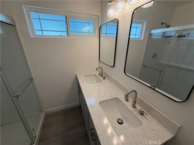 Primary bathroom with new flooring, new quartz-style countertops, dual sinks, new shower enclosure, and modern fixtures.