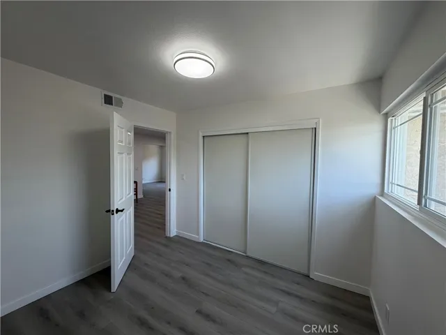  bedroom with wide-plank flooring, closet, updated light fixture, and large window for natural light.