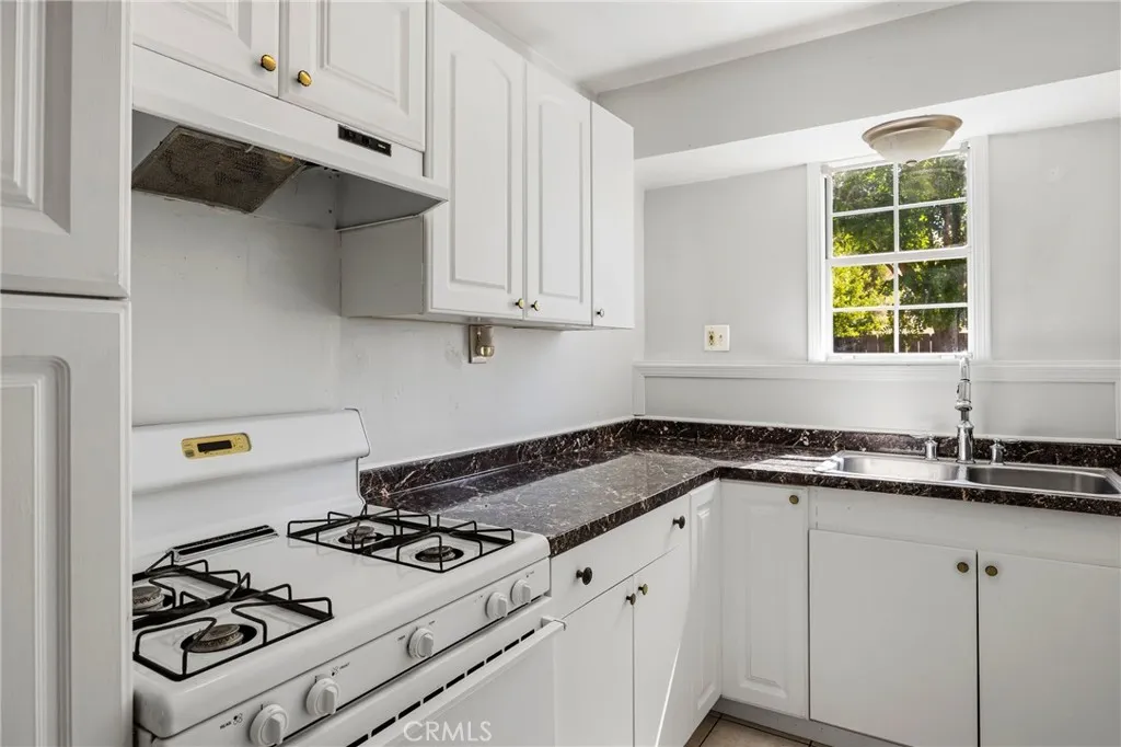 Guest House Kitchen – Efficient kitchen with ample cabinetry, generous counter space, and a bright window that brings in natural light and looks out to a private patio setting.