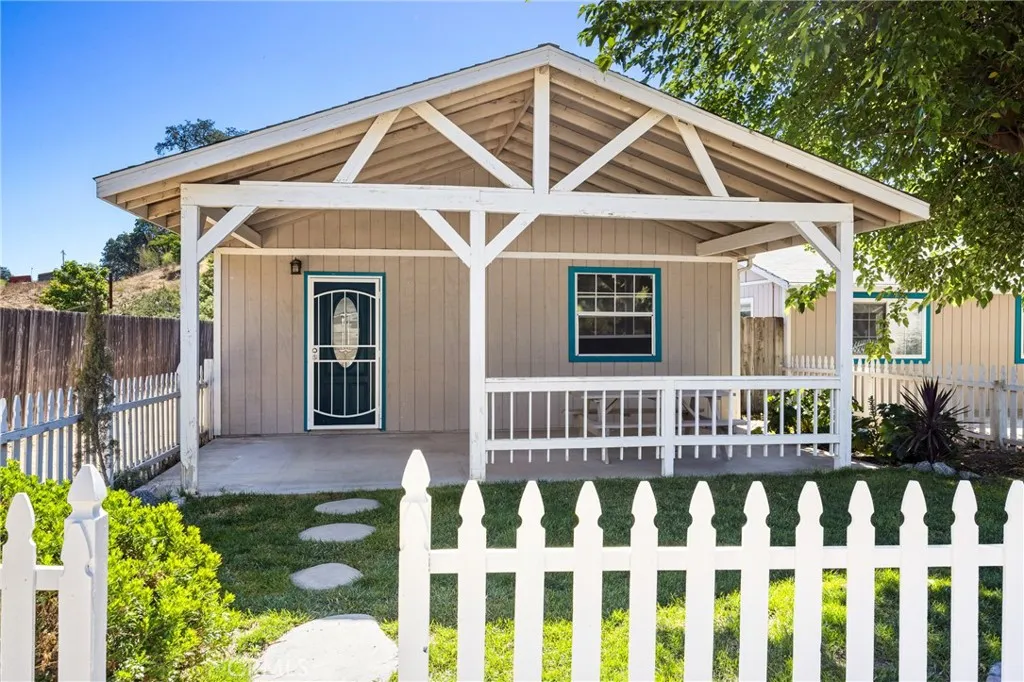 Guest House – Charming guest house with a welcoming covered porch, fenced yard, and cottage-style character, offering a private and inviting retreat.