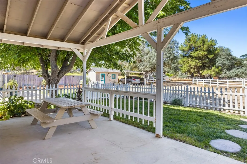Guest House Porch View – Relax on the covered porch overlooking the fenced yard, mature shade trees, and peaceful grounds surrounding the property.