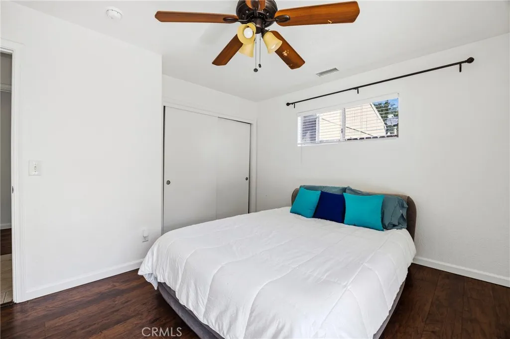 Spacious primary suite with a sliding-door closet, abundant natural light, and glass paned doors providing direct access to the backyard.
