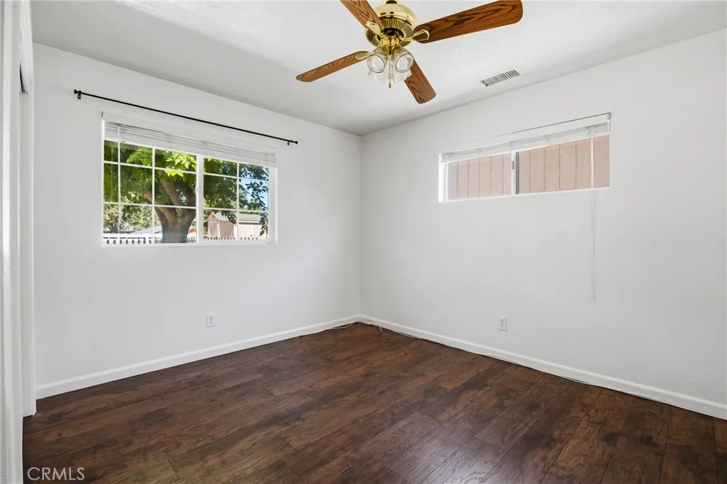 Bedroom #2 – Well-sized bedroom featuring wood laminate flooring, a ceiling fan and natural light from a large window.