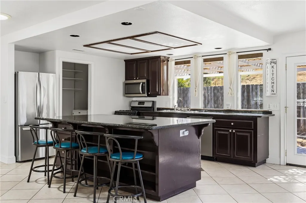 The Kitchen is filled with natural light from numerous windows and enjoys pleasant views of the backyard patio, adjacent is the laundry with pantry storage
