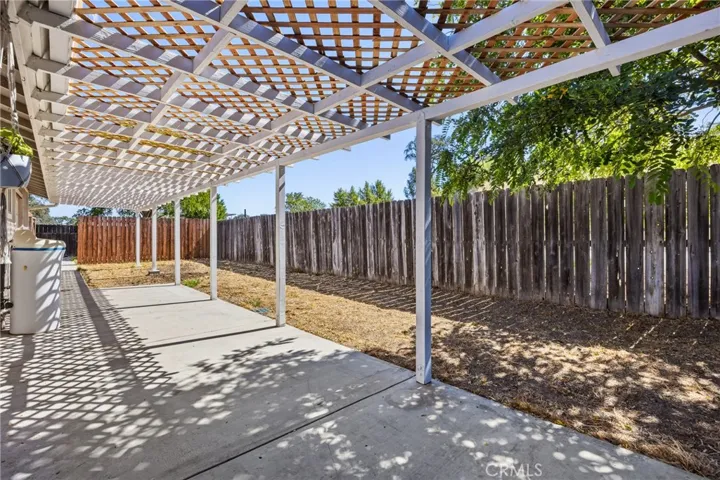 Backyard Patio – Covered patio with pergola-style shade, offering a spacious outdoor area for relaxing, dining, or entertaining. The fenced backyard provides privacy and room to enjoy the outdoors.