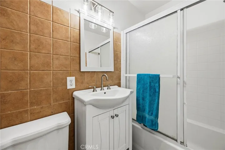 Bathroom – Full bathroom featuring an updated vanity, large mirror, and shower-over-tub combination with sliding glass doors.