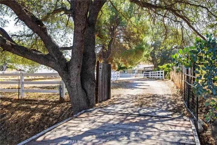 Cross the charming bridge over a seasonal creek and arrive through a canopy of mature oak trees. White rail fencing and a tree-lined driveway create a welcoming entrance that sets the tone for this peaceful country property.