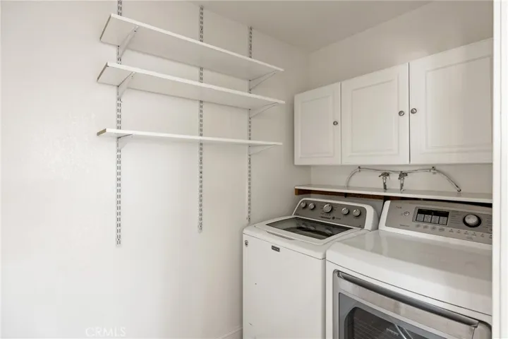 Laundry & Pantry Storage Area – Dedicated laundry room with built-in cabinetry and extensive shelving, providing convenient storage and organization.