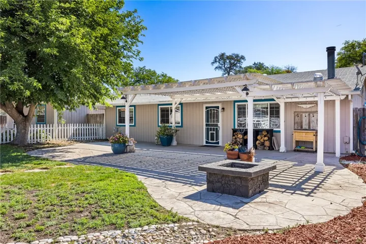 Front Patio – Inviting front patio featuring a pergola-covered entertaining area, built-in fire pit, and landscaped yard, creating a welcoming outdoor gathering space.
