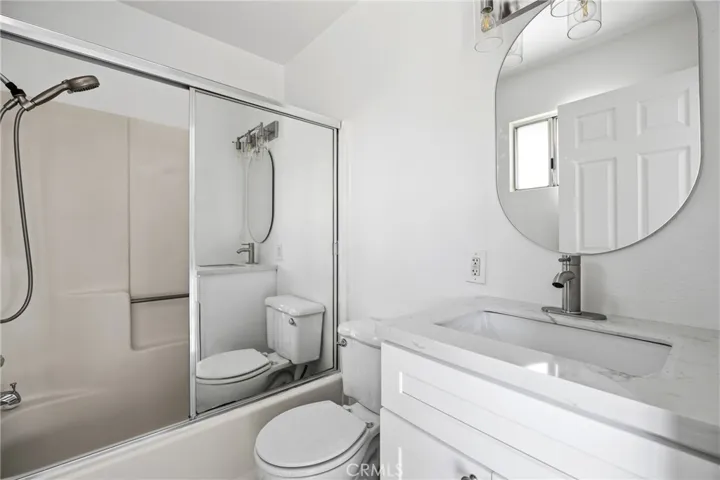 Primary Bathroom – Updated primary bathroom featuring a modern vanity, contemporary fixtures, and a tub-shower combination with sliding glass doors.