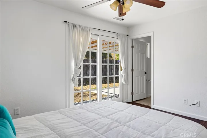 Primary Bedroom – Spacious primary bedroom featuring wood laminate flooring, a ceiling fan and sliding glass doors that open directly to the backyard patio, allowing for abundant natural light and indoor-outdoor access.