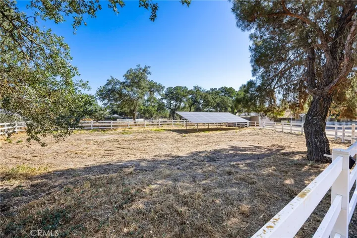 Pasture Area – Fenced pasture with open usable space, mature shade trees, and grid-connected solar panels providing on-site power production.