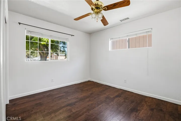 Bedroom #2 – Well-sized bedroom featuring wood laminate flooring, a ceiling fan and natural light from a large window.