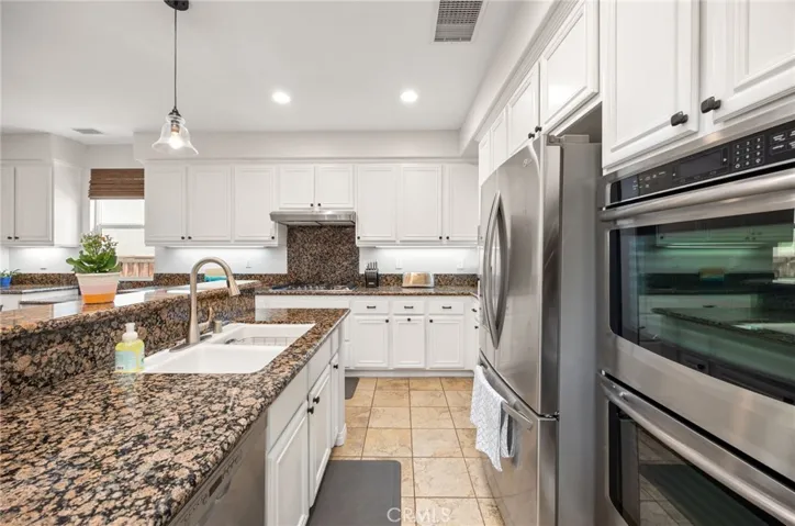 Remodeled Kitchen with Granite Countertops & Backsplash, White Cabinets with custom Hardware, Stainless Steal Appliances and Pendant Lighting