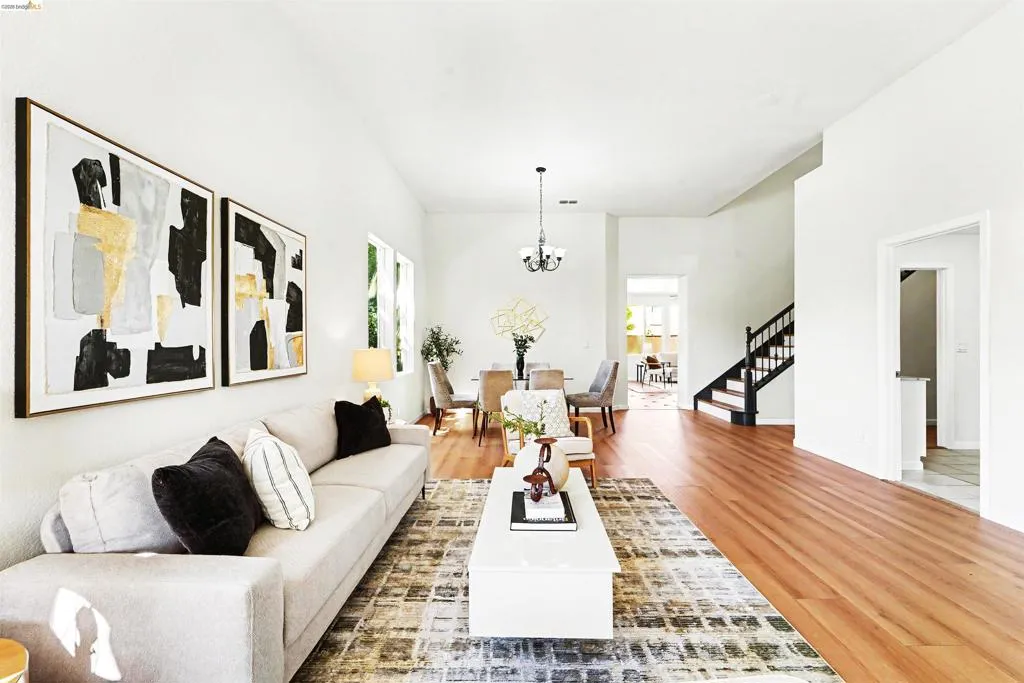 Open-concept living area featuring hardwood flooring, white walls, and a chandelier-style light fixture in the dining space