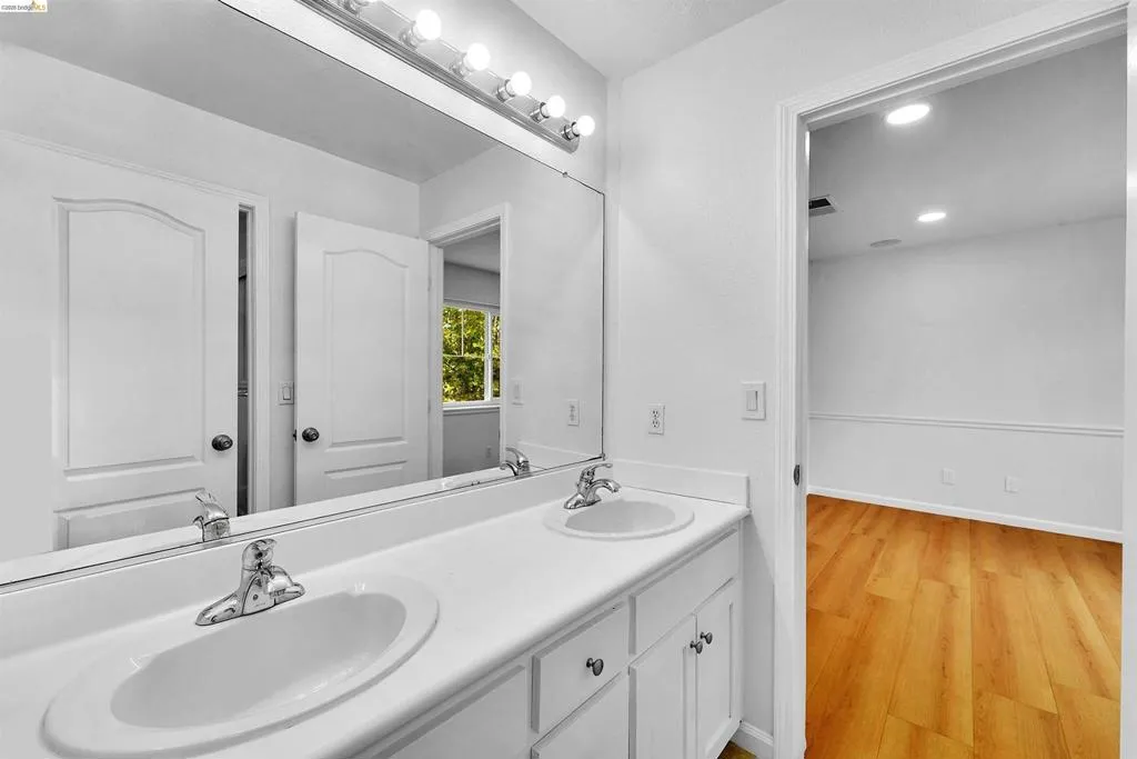 Double vanity featuring two integrated sinks, chrome faucets, and white cabinetry