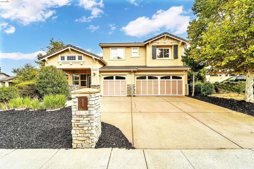 Two-story residence featuring a stucco exterior with stone accents and a covered entry