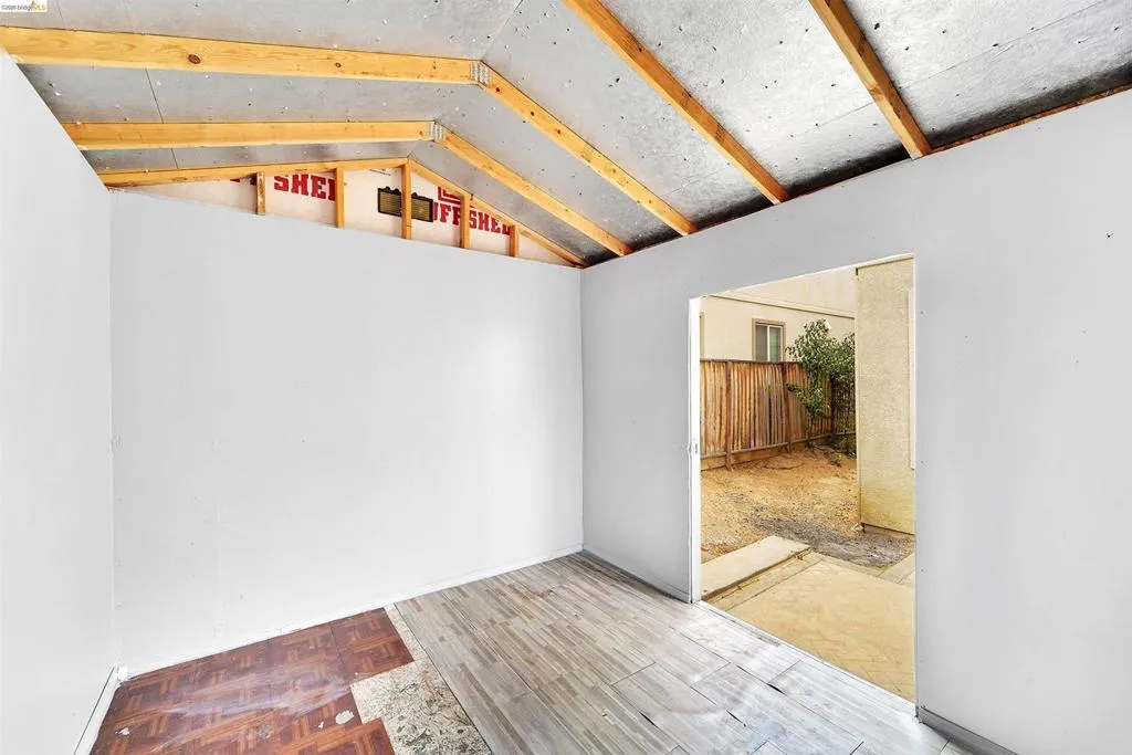 Interior space featuring partial wall framing, exposed ceiling joists, and mixed flooring