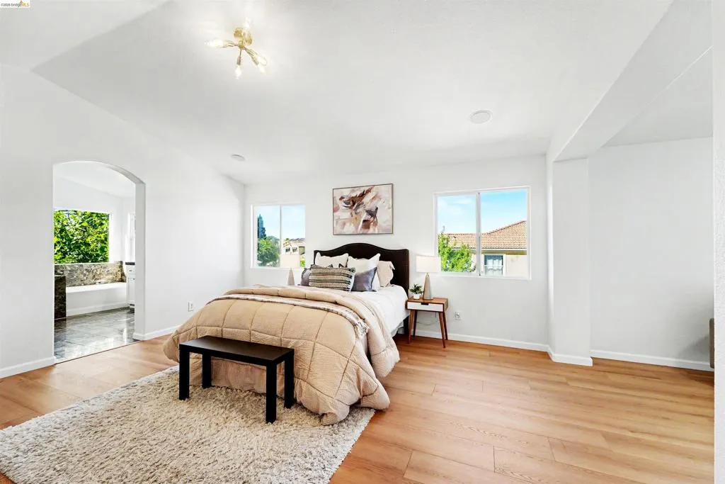 Spacious room featuring wood-finish flooring, white walls, and a recessed ceiling element
