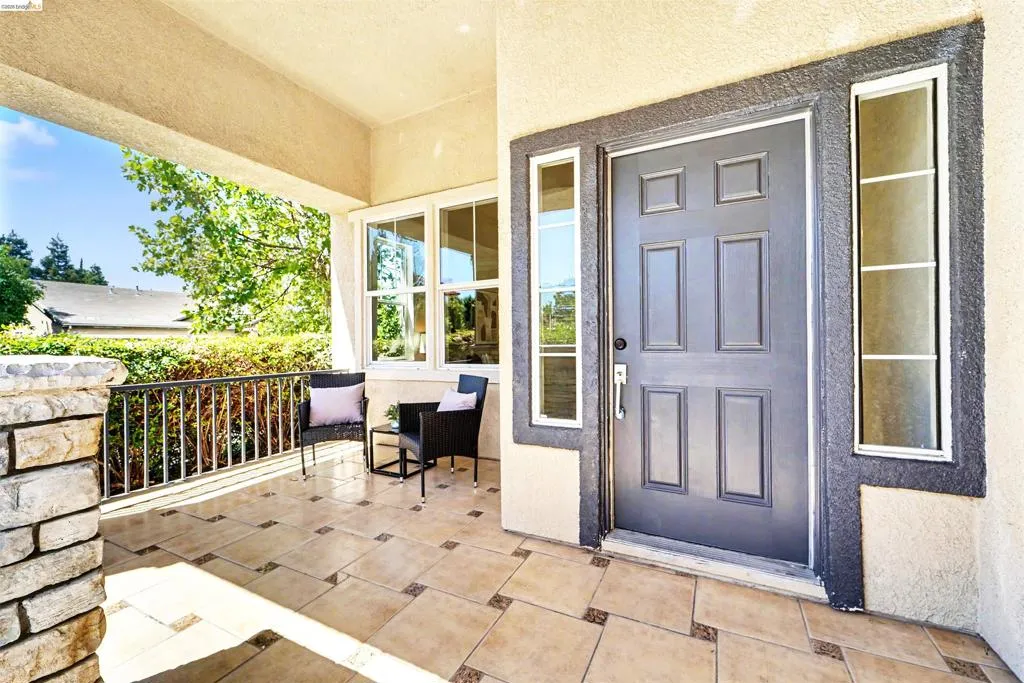 Inviting covered front porch with stone pillar detailing and a dark gray paneled entry door