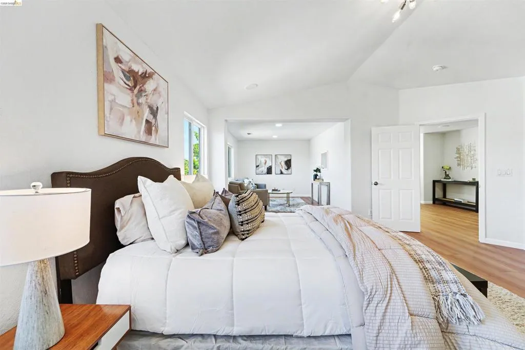 Spacious room with a vaulted ceiling, recessed lighting, and wood-finish flooring