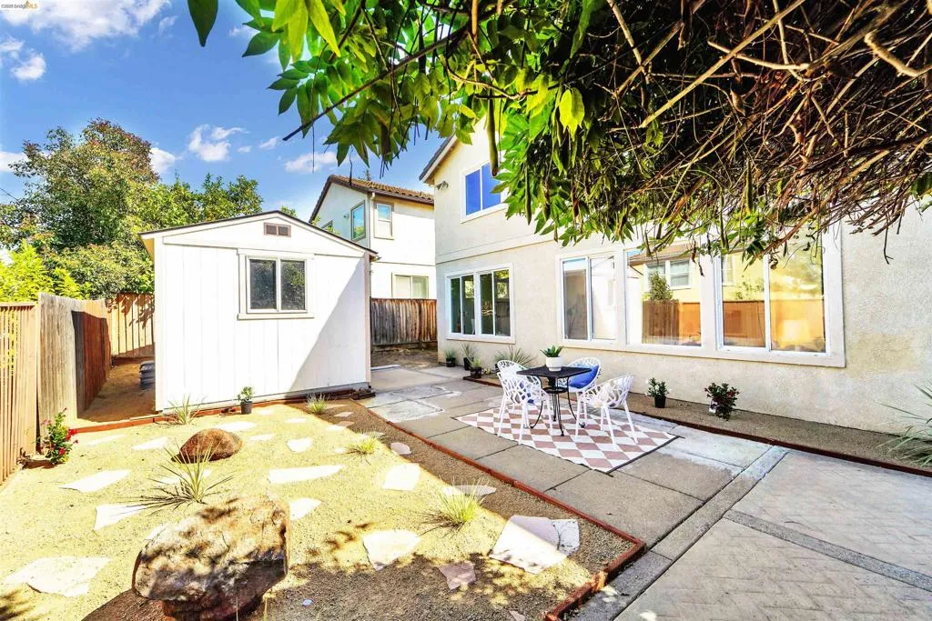 Spacious outdoor area featuring a modern shed, a concrete patio, and a low-maintenance landscape with flagstone pavers