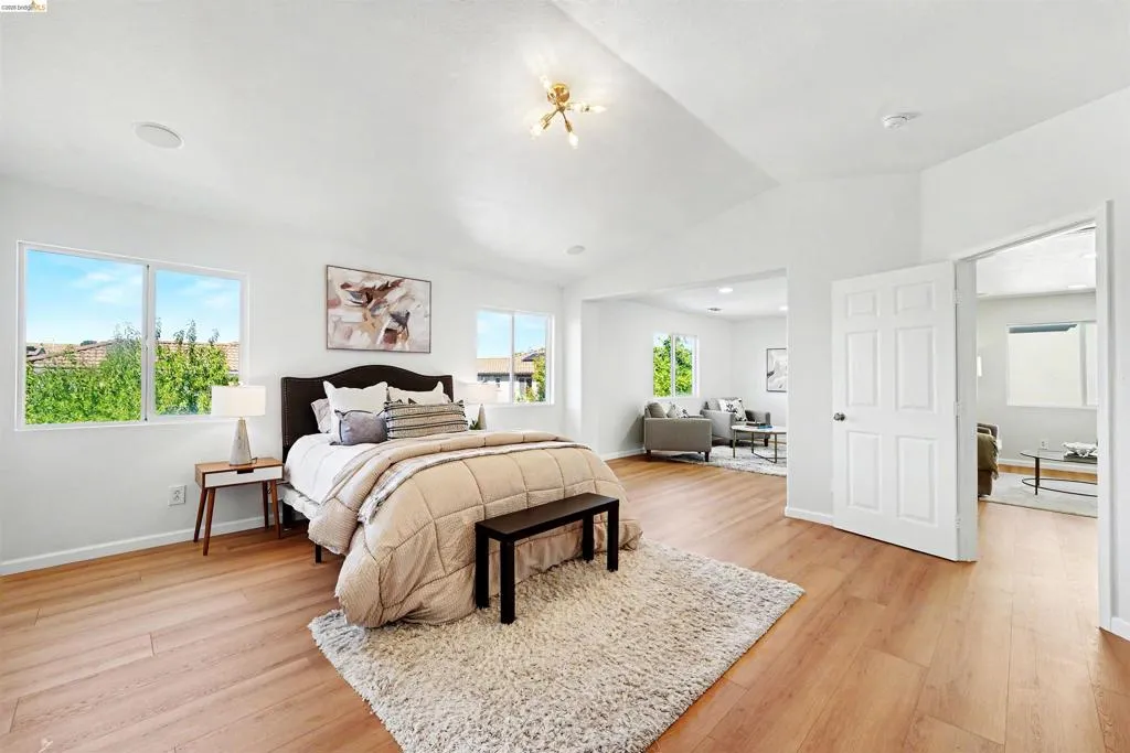 Spacious room featuring wood-finish flooring, vaulted ceilings, and multiple windows providing natural light