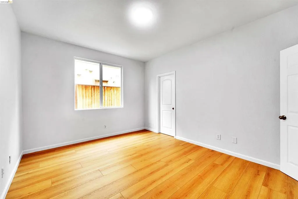 Bright interior space featuring wood-finish flooring, white walls, and a large window